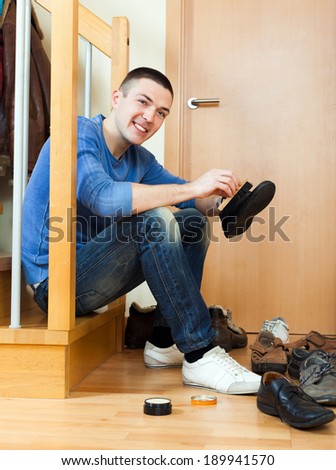 Happy man sitting on stairs and cleaning footwear