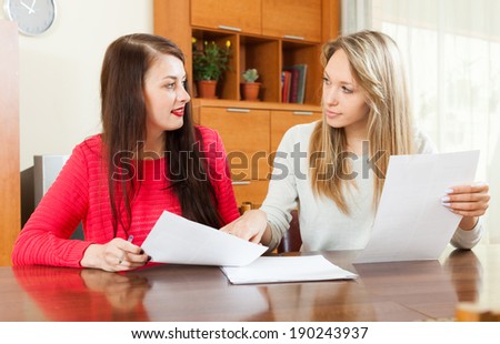 serious women looking financial documents at table in home or office