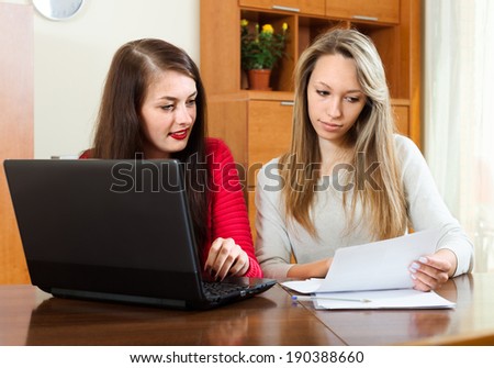 serious  lady with  documents and laptop at table in home interior