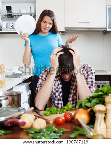 Family quarrel. Unhappy man with angry wife at home kitchen. Focus on girl