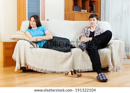 Family quarrel. Sad young couple after conflict on sofa in home