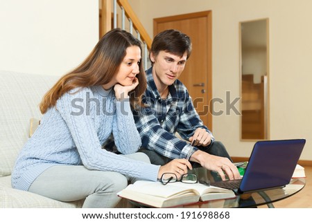 Serious guy and girl preparing for exam with laptop and books