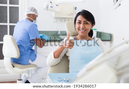 Happy woman sitting in dental chair after teeth cure giving thumb up Foto d'archivio © 