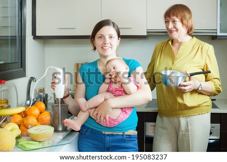 Happy women of three generations with blender cooking fruit puree in domestic kitchen at home