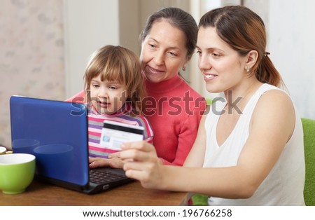 Happy family of three generations  shopping on internet from home, using laptop and paying with credit card