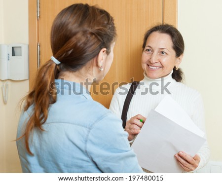 Smiling mature employee polling among people at home  door