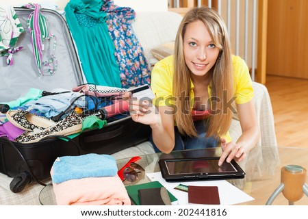 Attractive girl with packed suitcase booking hotel for vacation online with credit card