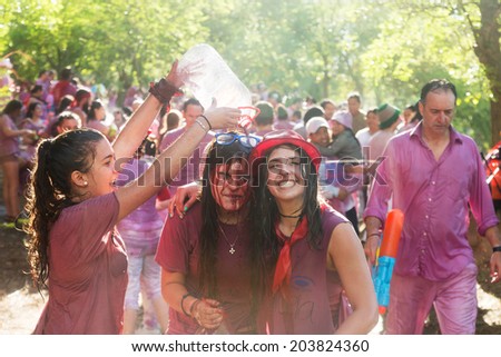 HARO, SPAIN - JUNE 29, 2014: Happy women during Batalla del vino - wine madness in Haro, La Rioja. People fighting with wine from botas, bottles and buckets