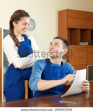 Happy  young workers in uniform with financial documents at table
