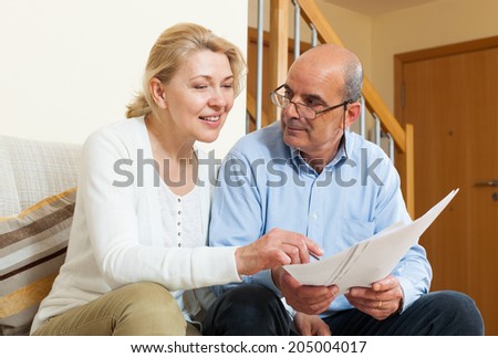 Elderly couple with financial documents on sofa in home