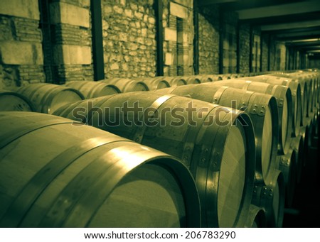 Aged photo of winery with  many wooden barrels in rows