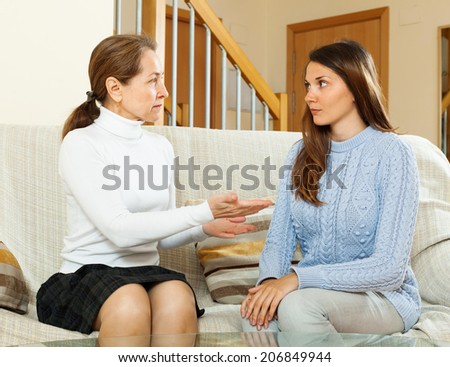 teenager daughter and mother having serious talking in home interior