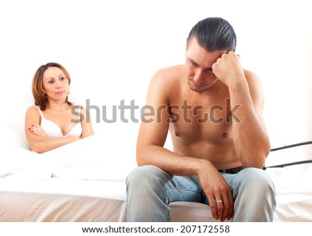 Depressed husband with problem sits on a bed in bedroom at home