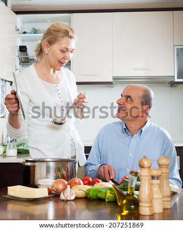 Happy mature woman and elderly senior cooking together at home kitchen