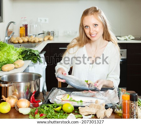 woman cooking full fish in sheet pan