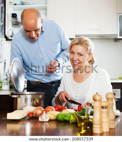 Ordinary mature couple cooking healthy food at home kitchen