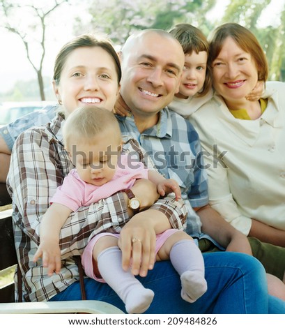 happy three generations family sitting at summer park