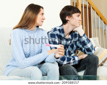 Sad worried woman with pregnancy test with unhappy man
