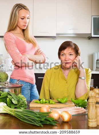 Sad mature female with daughter  sharing bad news in kitchen at home