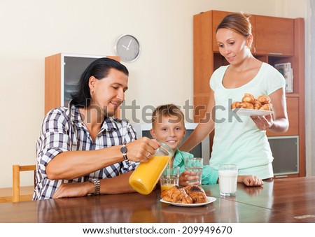 Happy couple with teenager son having breakfast in home interior