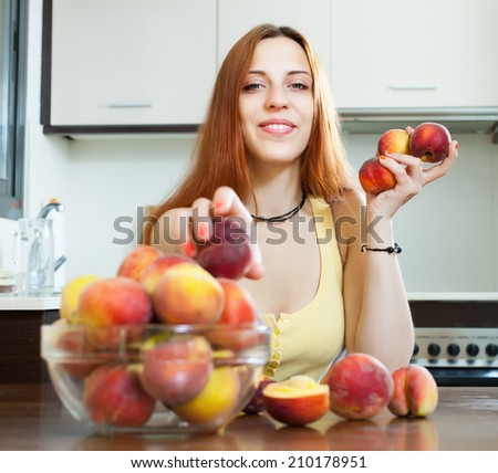 Happy pretty  woman holding peaches in home kitchen