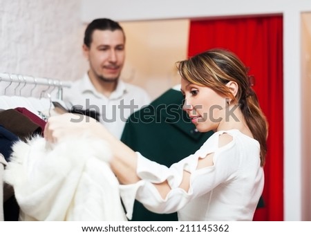 Ordinary couple choosing coat in fitting-room at market