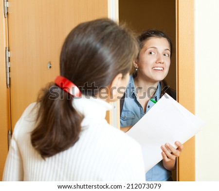 woman answer questions of outreach worker with papers at door in home