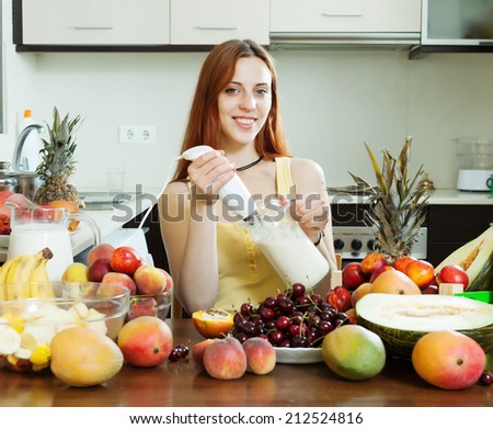 woman making fresh milk cocktail with blender from fruits at domestic kitchen