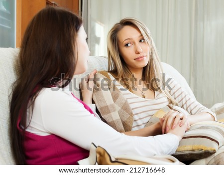 woman comforting crying friend at sofa in home