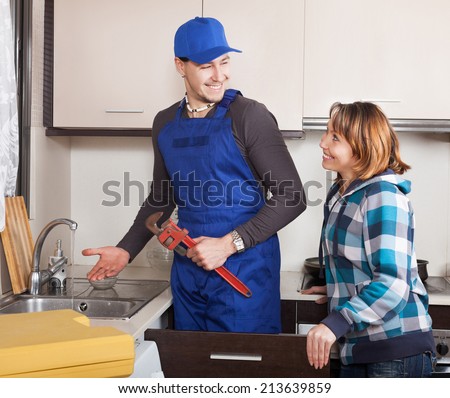 girl  watching as worker repairing  water lines in kitchen