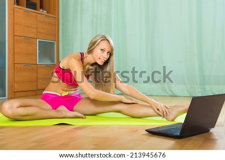 Persistent female doing yoga with laptop at home and smiling