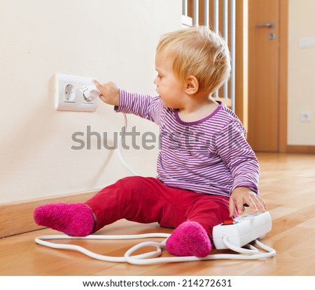 Toddler playing with extension cord and outlet at home