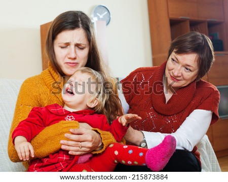Young mother has problems. Mature woman comforting adult daughter with crying baby in living room at home
