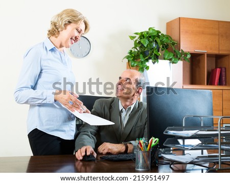 scene of two aged and smiling co-workers in office