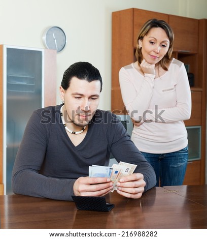 Man counting money, woman watching him in home