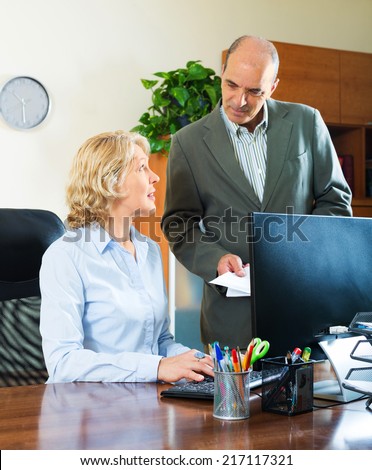 Ordinary office scene with two mature and serious co-workers