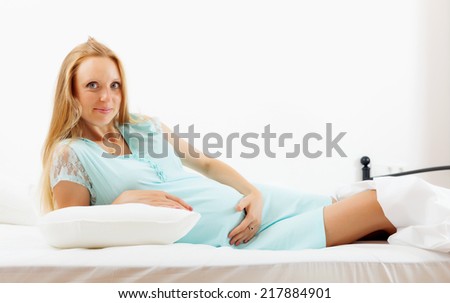 long-haired pregnancy woman in nightdress lying on bed