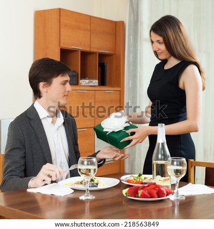 Pretty girl  giving gift  to man at table during romantic dinner