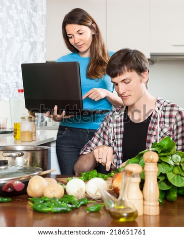 Nice girl shows the new recipe at kitchen table