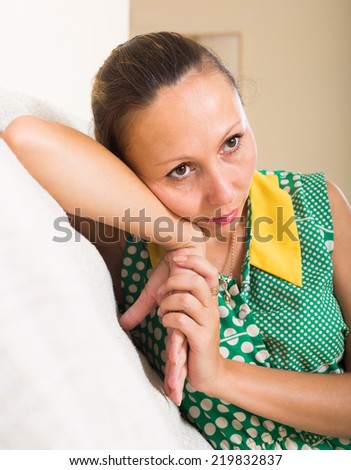 Sad and lonely middle-aged woman sitting on couch at home