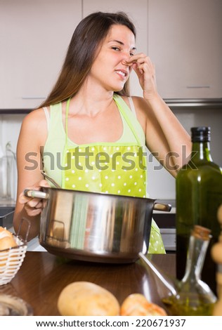 Unpleased woman pinched her nose avoiding bad smell from pan