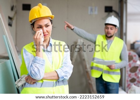 Asian woman engineer crying because she has been fired by her foreman who standing in background and making pointing gesture. Foto stock © 