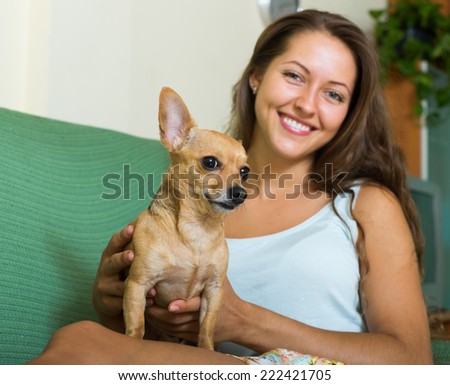 Smiling girl holding Russkiy Toy Terrier at home. Focus on dog