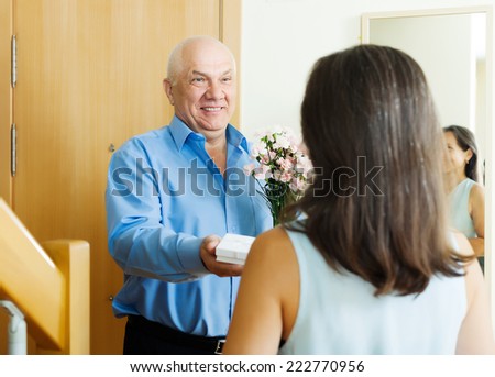 Smiling mature man giving jewel in box to woman at home door