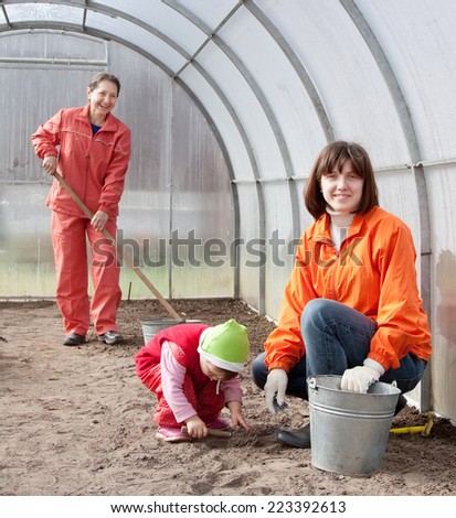 Happy family sows seeds in soil at greenhouse
