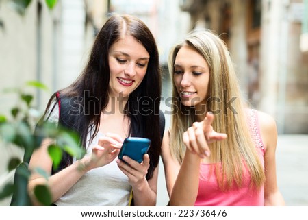 Two nice girls finding path with smartphone outdoor