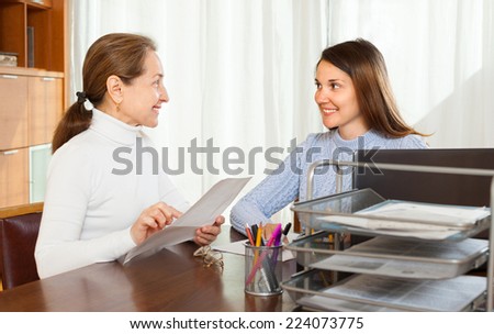 woman filling questionnaire for mature employee with paper at door