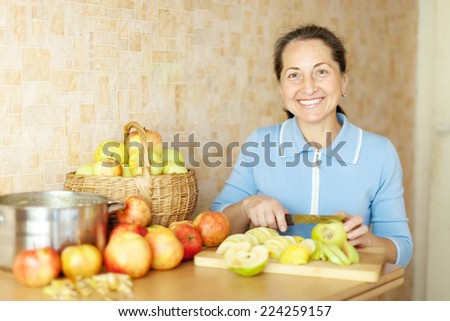 Woman cuts apples for apple jam in kitchen