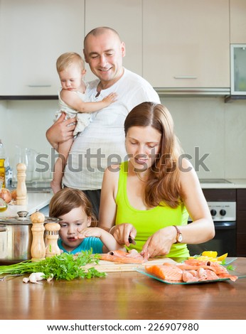 A happy and wonderful family of four cooking red fish in the home kitchen