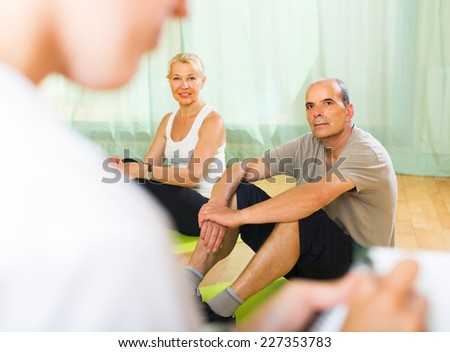 Medical staff watching yoga class for pensioners indoor. Focus on man